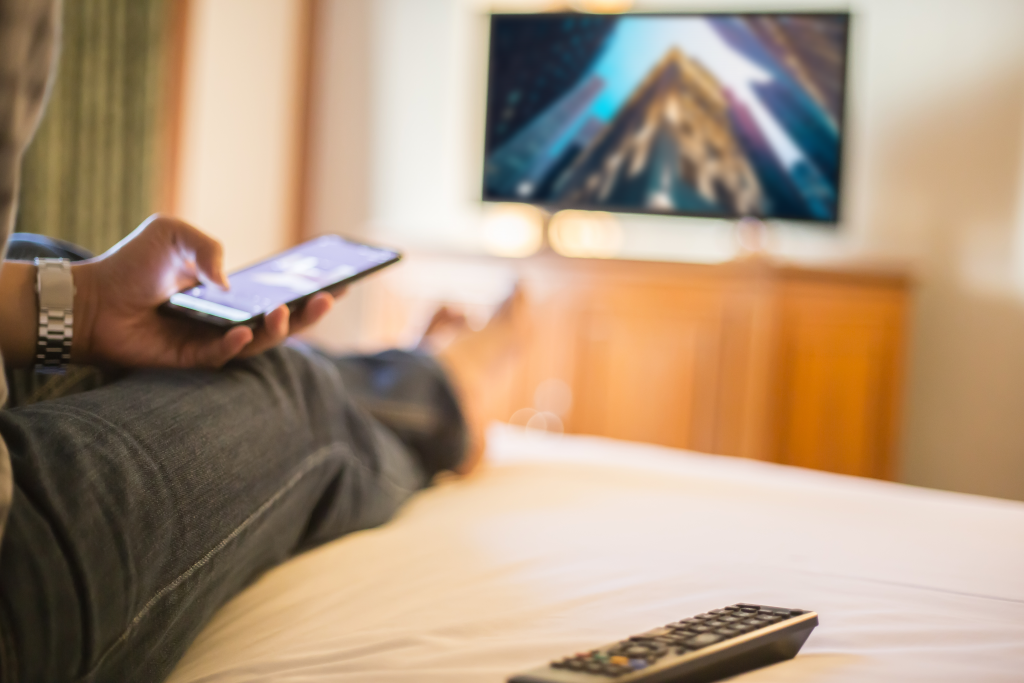 person sitting on bed using mobile phone and TV