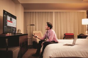 person sitting on hotel room bed watching TV