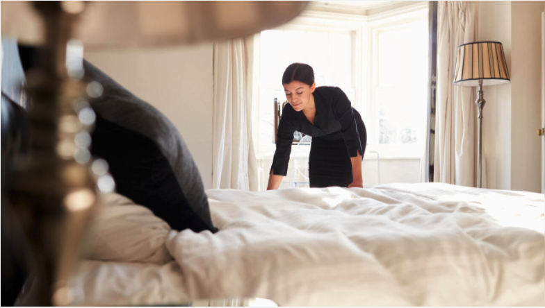woman tidying hotel room bed