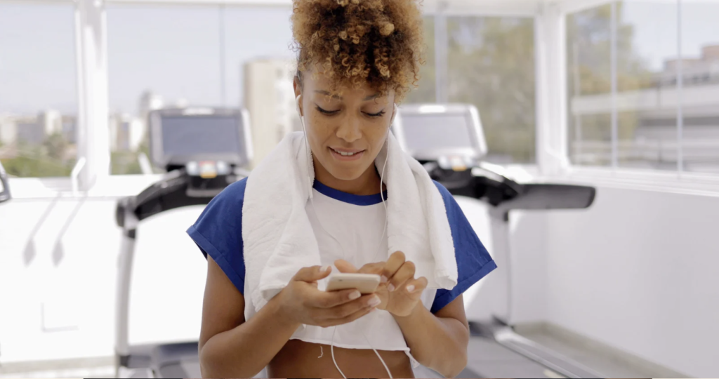 woman in exercise facility using mobile phone
