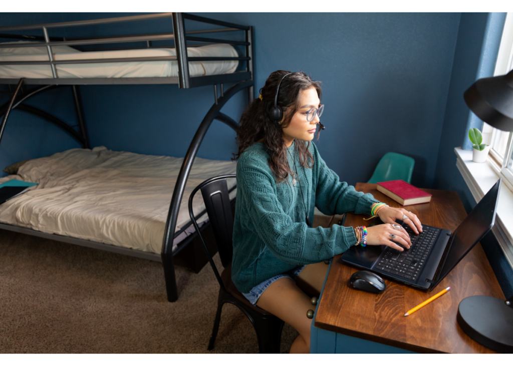 student using laptop in dorm room