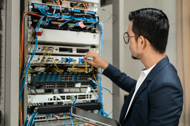 a worker adjusting settings in a network equipment room