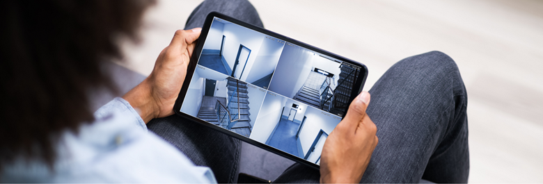 a person holding a tablet showing hotel interior common area images from a CCTV camera