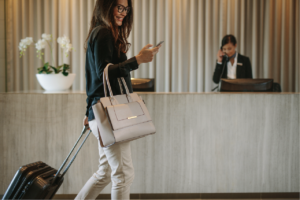traveler walking past front desk with luggage while looking at phone, using customized network solutions