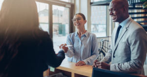 guests smiling and speaking with front desk attendant