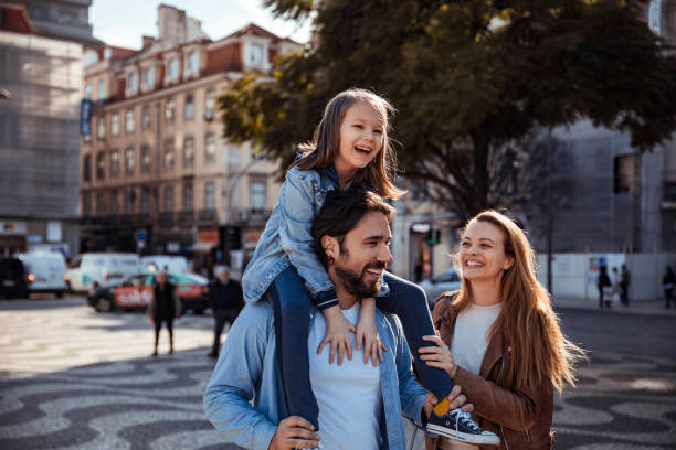 couple walking through city, with child on dad's shoulders