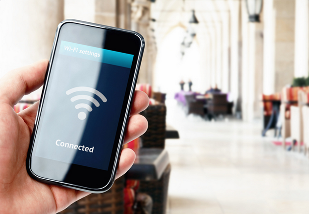 A guest holding a mobile device in a hotel lobby. The device screen indicates it's connected to the hotel Wi-Fi.
