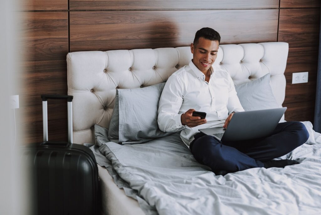 happy guests is using wifi with laptop and mobile phone in hotel room