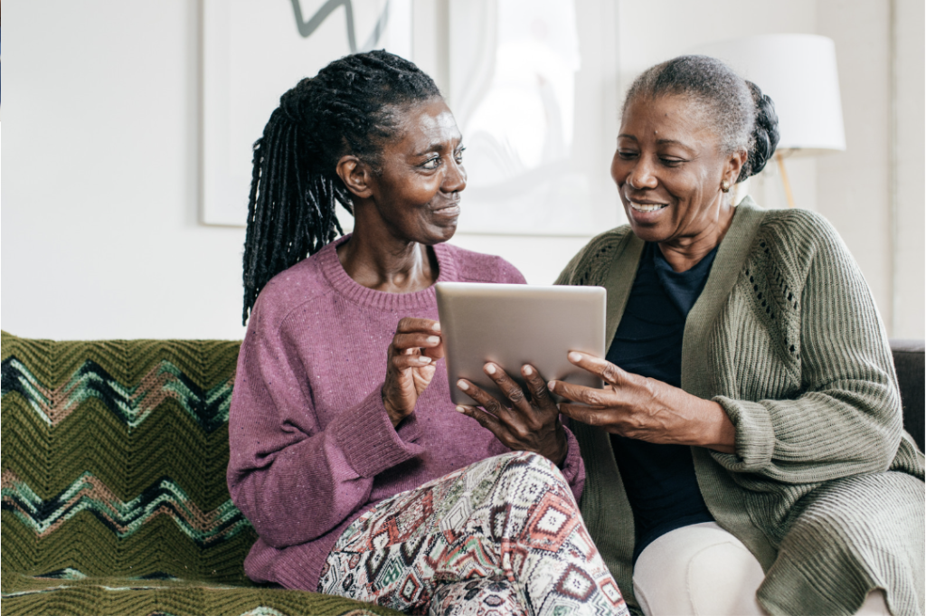 two senior living residents discussing content on a tablet
