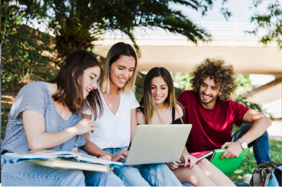 students outdoors sharing laptop