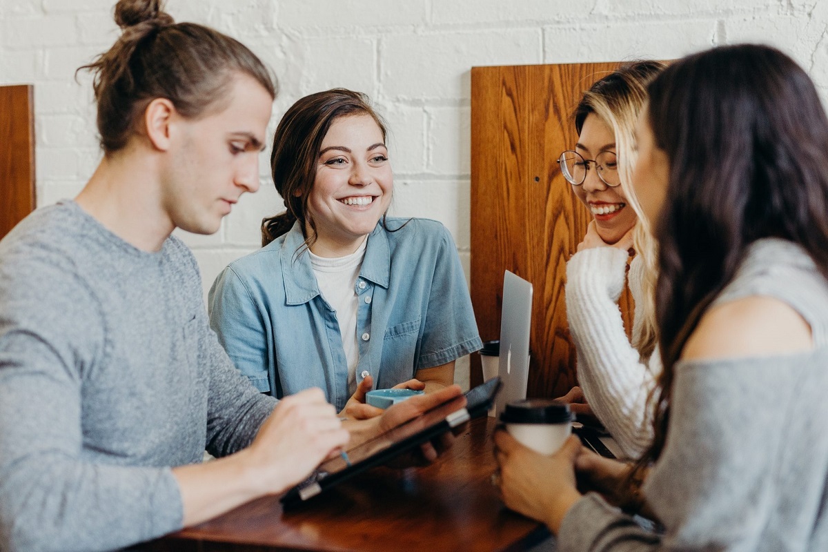 students gathering at coffee shop using tablet to order